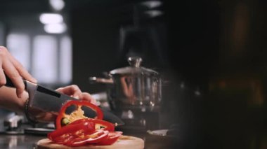 Tahta üzerinde sebze doğrayan bir kadının elleri.