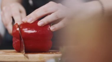 Tahta üzerinde sebze doğrayan bir kadının elleri.