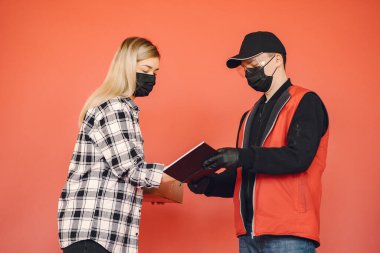 Kadınla birlikte sağlık maskeli teslimatçı.