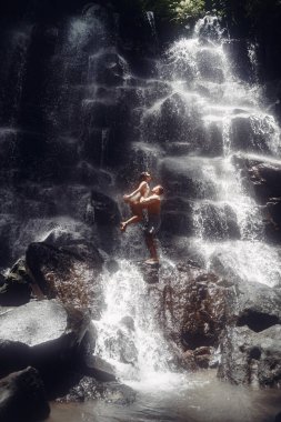 Çift büyük bir şelalenin altında duruyor.