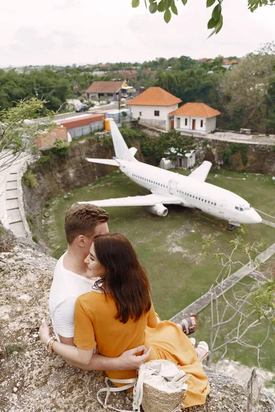 Coppia seduta su una roccia e guardando un aereo — Foto Stock