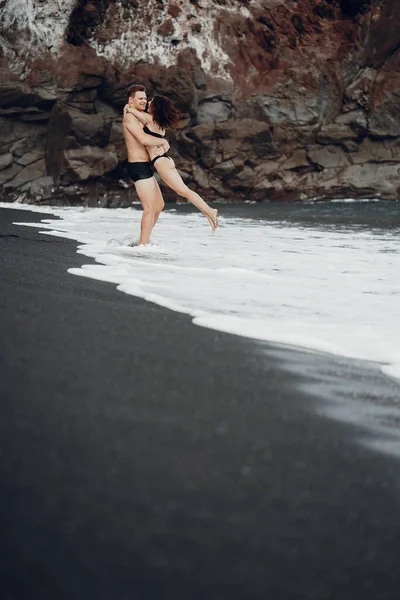 Elegante coppia su una spiaggia vicino a scogli — Foto Stock