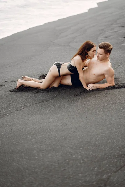 Casal elegante em uma praia perto de rochas — Fotografia de Stock