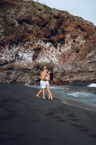 一对优雅的夫妇在岩石附近的海滩上 — 图库照片