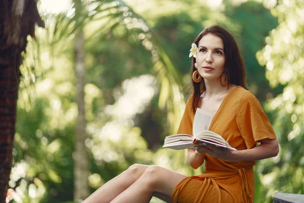 Vrouw zitten met een boek op een jungle achtergrond — Stockfoto