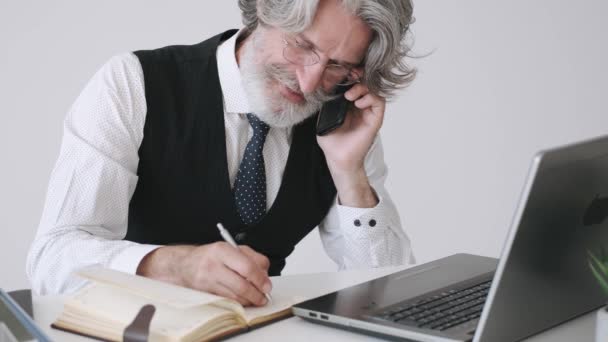 Стильный старый бизнесмен разговаривает по телефону в офисе — стоковое видео