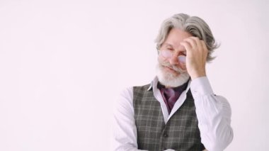 Beyaz arka planda duran smokinli yakışıklı bir son sınıf öğrencisi.