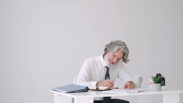 स्मार्ट देखावा म्हातारा माणूस टेबलवर काम — स्टॉक व्हिडिओ