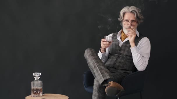 Brutal senior homme en tux tenant verre avec whisky et cigare fumant — Video