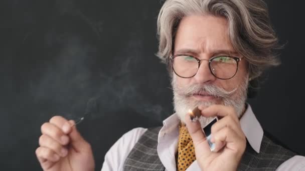 Brutal senior man i smoking håller glas med whisky och rökning cigarr — Stockvideo