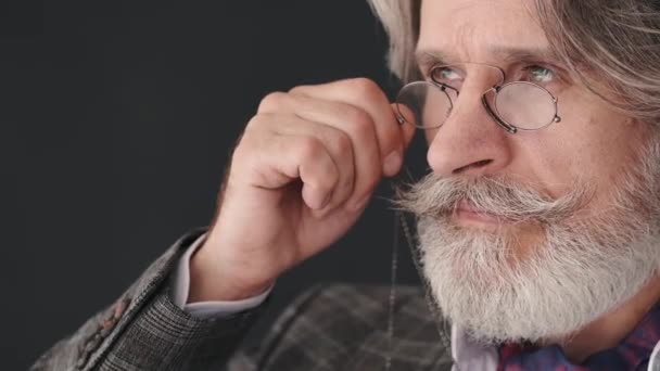 Snygg skäggig gammal man som håller glasögon och tittar genom dem — Stockvideo