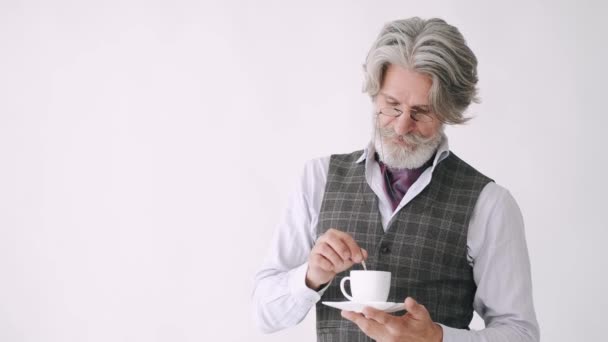 Чоловік старшого стилю з чашкою кави стоїть на білому тлі — стокове відео