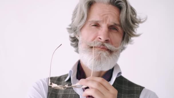 Tänksam senior man i smoking med glasögon stående mot vit bakgrund — Stockvideo