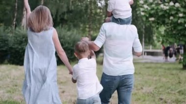 İki oğlu olan bir aile yaz parkında birlikte yürüyor.