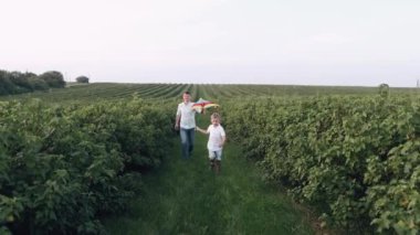 Baba ve oğul yeşil alanda uçurtma uçuruyorlar.