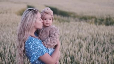 Küçük bir kızı olan güzel bir anne buğday tarlasında duruyor.
