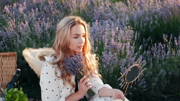 Mooie blonde vrouw in een jurk zittend in het lavendelveld — Stockvideo