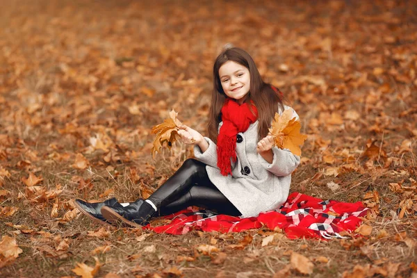 Cute little girl w szarym płaszczu gra w jesiennym parku — Zdjęcie stockowe