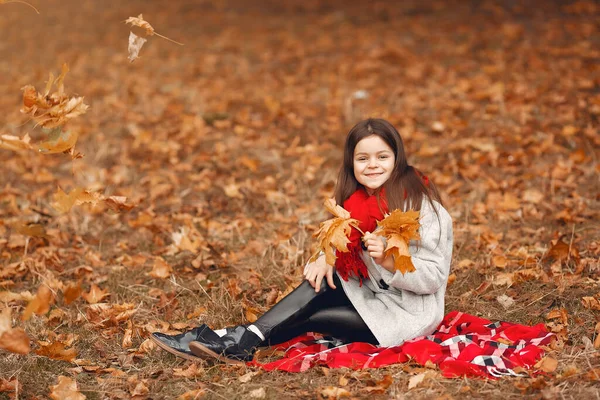 Cute little girl w szarym płaszczu gra w jesiennym parku — Zdjęcie stockowe