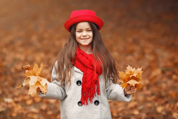 Cute little girl w szarym płaszczu gra w jesiennym parku — Zdjęcie stockowe
