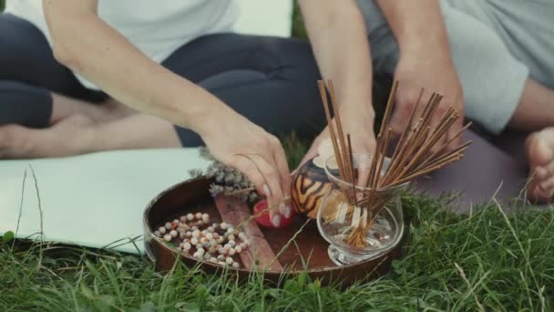 Närbild av doftpinnar och ljus på en träplatta på gräset — Stockvideo