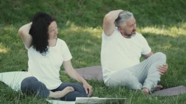 Orta yaşlı adam ve kadın dışarıda jimnastik yapıyor.