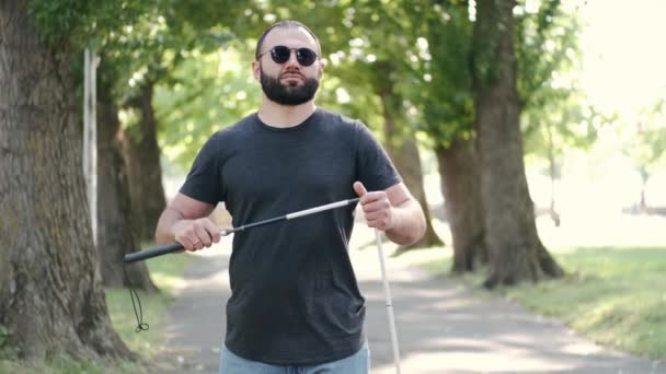 Gehandicapte man vouwt een witte stok in een park — Stockvideo