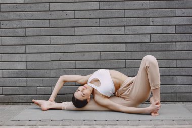 Karanlık bir şehir duvarına karşı gelişmiş yoga yapan bir kadın.