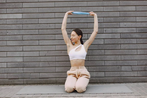 Femme pratiquant le yoga avancé contre un mur urbain sombre — Photo