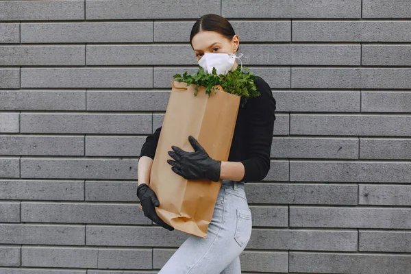 Meisje in beschermende masker houdt verpakking met producten — Stockfoto