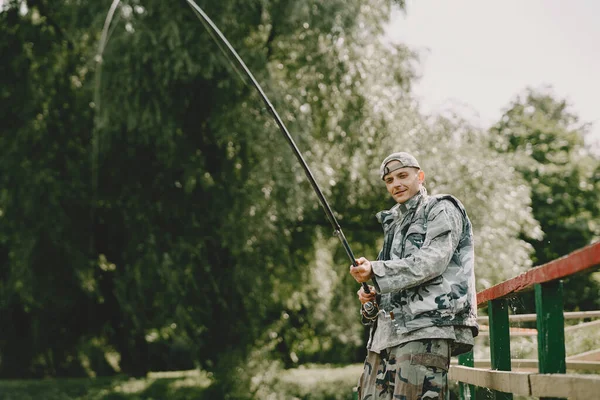 Hombre pescando y sostiene la caña de pescar — Foto de Stock