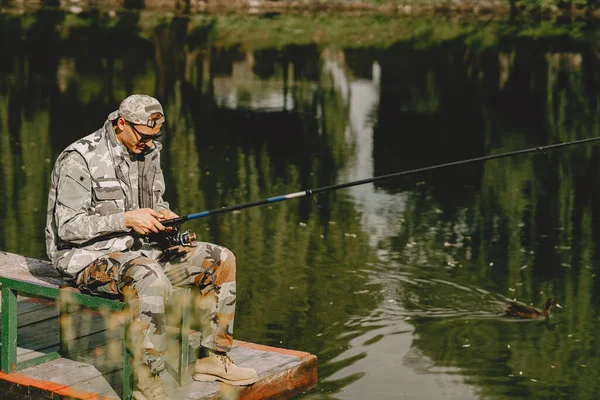 Hombre pescando y sostiene la caña de pescar — Foto de Stock