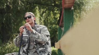 Özel üniformalı ve güneş gözlüklü bir genç göl kıyısında balık tutuyor.