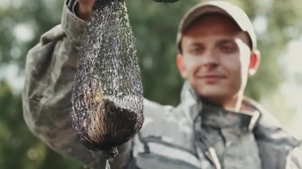 Primer plano de un pescador que atrapó un pez en una red de emboscada y mirándolo — Vídeo de stock