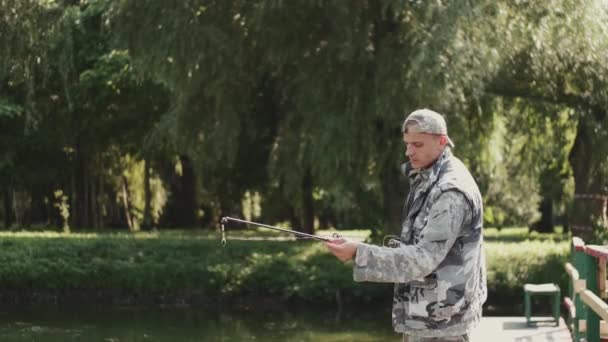 Jistý rybář připravuje prut k rybolovu u rybníka — Stock video