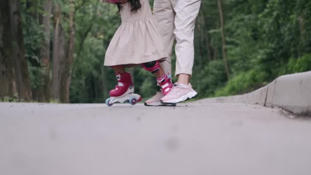 Mãe e filha em patins e capacete estão na estrada em um parque — Vídeo de Stock