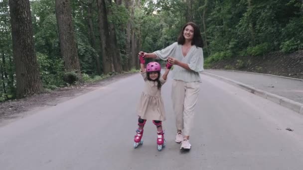 Madre e hija en patines y casco están en la carretera en un parque — Vídeo de stock