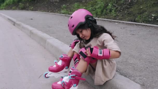 Gadis kecil bertopi baja meletakkan peralatan pelindung di jalan. — Stok Video