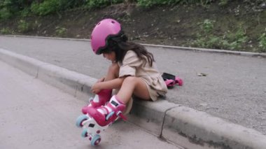 Miğferli küçük kız yola koruyucu ekipman koyuyor.