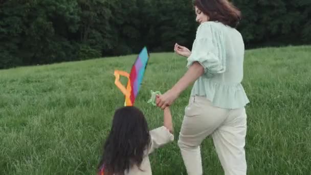 Mãe e filha feliz andando com pipa no gramado — Vídeo de Stock