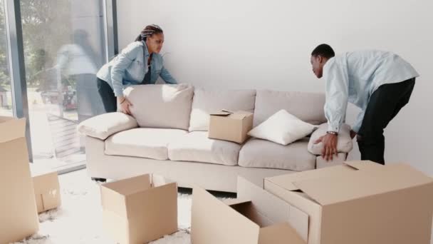 Hombre y mujer africanos están reemplazando un sofá en un nuevo apartamento moderno — Vídeos de Stock