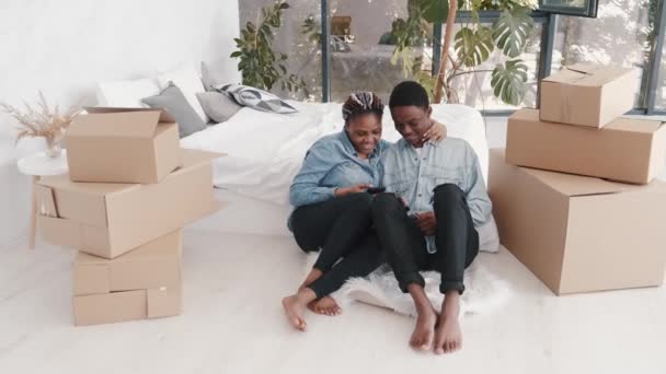 Młoda para afro-amerykańska siedzi w nowoczesnym mieszkaniu z pudełkami — Wideo stockowe