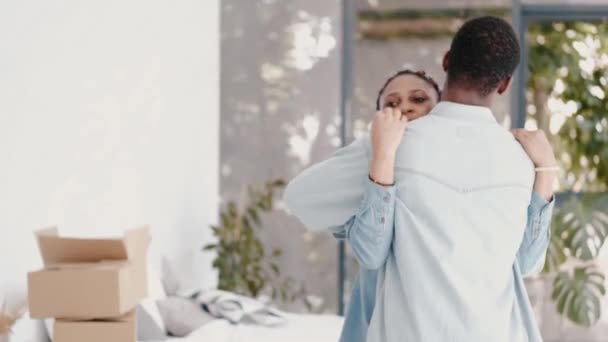 Afican-amerikanska paret kramas i ett nytt hus. — Stockvideo