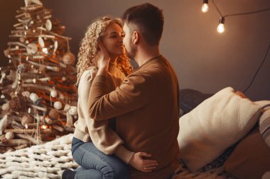 Noel ağacının yanında oturan zarif bir çift.