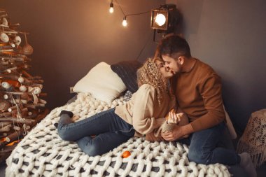 Noel ağacının yanında oturan zarif bir çift.