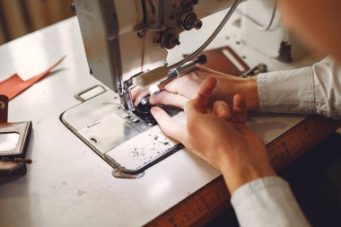 Stüdyodaki adam deri eşya üretiyor.