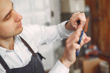 Stüdyodaki adam deri eşya üretiyor.