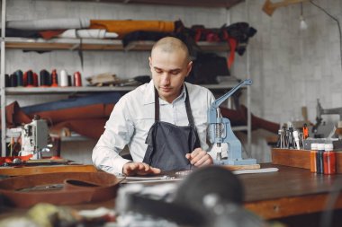 Stüdyodaki adam deri eşya üretiyor.