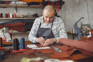 Stüdyodaki adam deri eşya üretiyor.