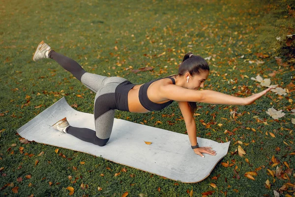 Sports girl in a black top training in a autumn park — Stock Photo, Image